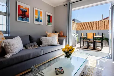 a living room with a couch and a glass table at Von Chambers Blouberg in Cape Town
