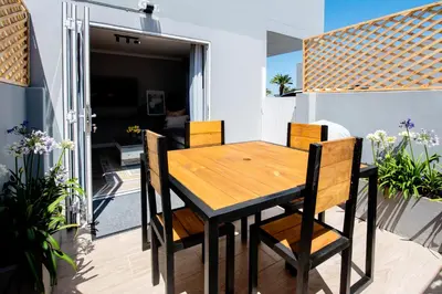 a wooden table and chairs on the balcony of a house at Von Chambers Blouberg in Cape Town