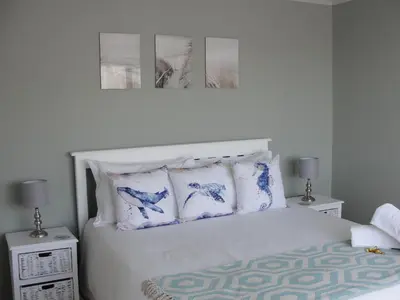 a bedroom with a bed with blue and white pillows at 113 Reasons Self Catering in Cape Town