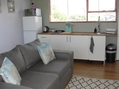 a living room with a couch and a kitchen at 113 Reasons Self Catering in Cape Town