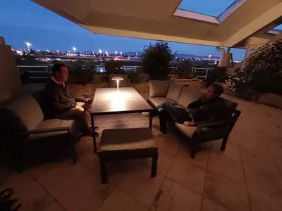 two men sitting on couches on a patio at night at Dolphin Beach Estate 131sm in Cape Town