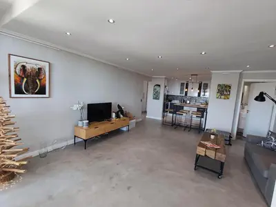 a living room with a couch and a television in it at Dolphin Beach Estate 131sm in Cape Town