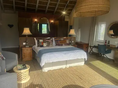 a bedroom with a bed and a couch and a mirror at Zeven Eike Homestead in Stellenbosch