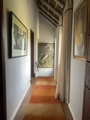 a hallway with two paintings on the walls and a rug at Zeven Eike Homestead in Stellenbosch