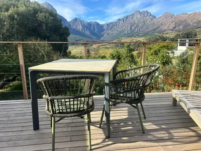 a table and two chairs on a deck with mountains at Zeven Eike Homestead in Stellenbosch