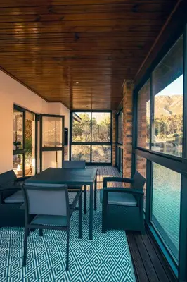 a house with a deck with a table and chairs at Wildeberg Dam House Cottage in Franschhoek