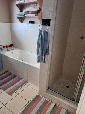 a bathroom with a shower and a tub and a towel at Kraaifontein Family Home in Cape Town