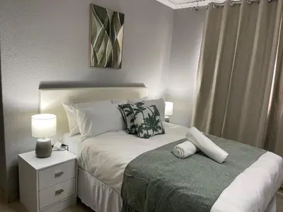 a bedroom with a bed and a night stand with a lamp at Maita Guest in Cape Town