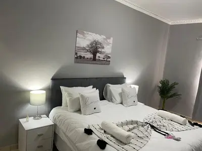 a white bedroom with a bed with white sheets and pillows at Maita Guest in Cape Town