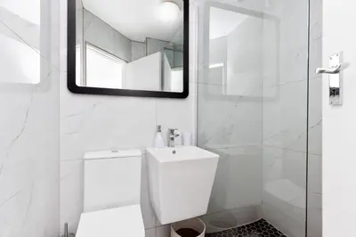 a white bathroom with a toilet and a mirror at The Bay A602 in Cape Town