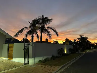 a fence in front of a house with a palm tree at Strand Holiday home in Cape Town