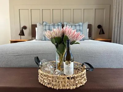a bottle of wine and flowers in a basket on a bed at The Cliff Villa Boutique Guesthouse in Hermanus