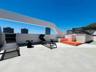 a patio with two chairs and a couch on a roof at Seapoint Solace in Cape Town