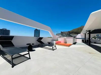 a patio with two chairs and a couch on a roof at Seapoint Solace in Cape Town