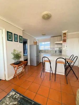 a kitchen with a table and chairs and a refrigerator at The Hermanus holiday self catering beach club in Hermanus