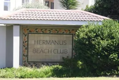 a sign for a beach club in front of a building at The Hermanus holiday self catering beach club in Hermanus