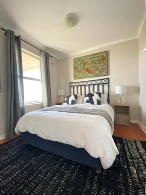 a bedroom with a large bed with pillows on it at The Hermanus holiday self catering beach club in Hermanus
