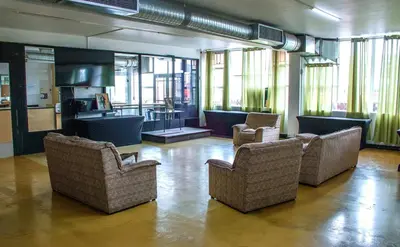a large room with chairs and tables and windows at Montana Backpackers Cape Town in Cape Town