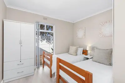 a bedroom with two beds and a desk and a window at Ravens 9A in Cape Town