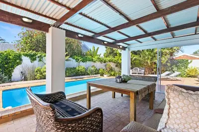 an outdoor patio with a table and chairs and a pool at Ravens 9A in Cape Town