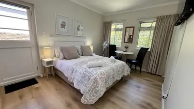 a bedroom with a bed and a table and chairs at Paradysrus in Stellenbosch
