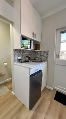a kitchen with white cabinets and a black dishwasher at Paradysrus in Stellenbosch