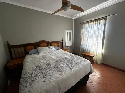 a bedroom with a bed and a fan and a window at Jacob's Rest in Cape Town