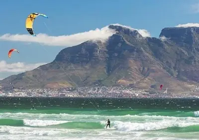 a man kite surfing in the ocean with a mountain at Pet friendly & Close to Beach at 2 Saasveld in Bloubergstrand
