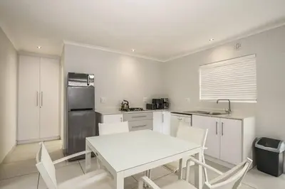 a kitchen with a white table and white chairs at Pet friendly & Close to Beach at 2 Saasveld in Bloubergstrand