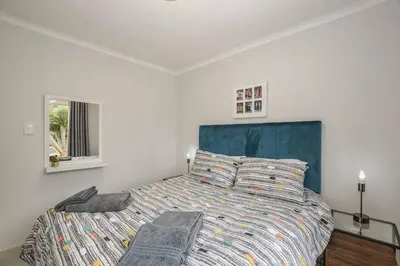 a bedroom with a large bed with a blue headboard at Pet friendly & Close to Beach at 2 Saasveld in Bloubergstrand