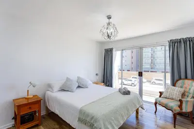 a bedroom with a bed and a window and a chair at Ocean View B104 by CTHA in Bloubergstrand