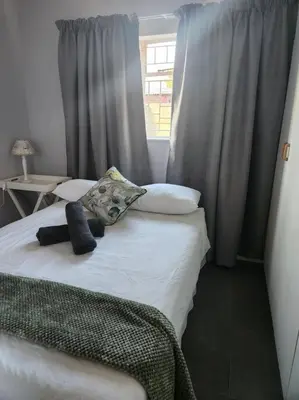 a bed in a room with a window and a bed with pillows at HartebeesDen in Worcester