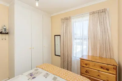 a bedroom with a bed and a dresser and a window at Secured 3-Bedroom Townhouse in Cape Town