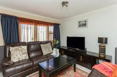 a living room with a leather couch and a flat screen tv at Secured 3-Bedroom Townhouse in Cape Town