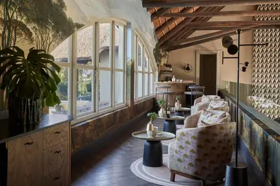 a room with two chairs and a table and windows at The Thatch House Boutique Hotel, Hermanus in Hermanus