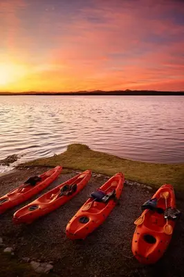 three kayaks on the shore of a lake at sunset at The Thatch House Boutique Hotel, Hermanus in Hermanus