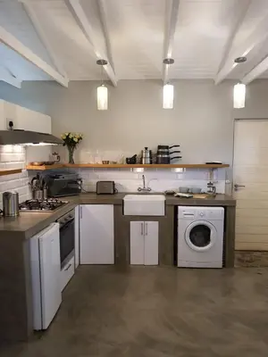 a kitchen with a sink and a washing machine at Blouberg Rise Cottage in Cape Town