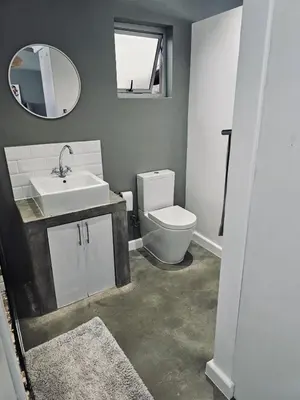 a bathroom with a toilet and a sink and a mirror at Blouberg Rise Cottage in Cape Town