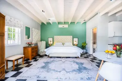 a bedroom with a white bed and a green wall at 1-Bed Cottage ,Sleeps 3, Walk to Boys High and Bossa in Paarl
