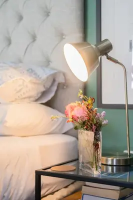 a table with a lamp and a vase with flowers on it at 1-Bed Cottage ,Sleeps 3, Walk to Boys High and Bossa in Paarl