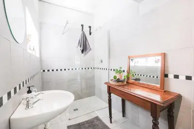 a bathroom with a sink and a mirror on a table at 1-Bed Cottage ,Sleeps 3, Walk to Boys High and Bossa in Paarl