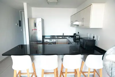 a kitchen with a black counter and white appliances at Beachside Escape in Cape Town