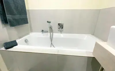 a white bath tub with a shower in a bathroom at Beachside Escape in Cape Town