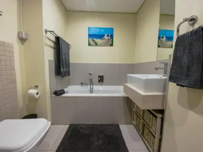 a bathroom with a sink and a tub and a toilet at Beachside Escape in Cape Town