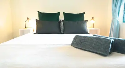a bedroom with a large white bed with green pillows at Beachside Escape in Cape Town