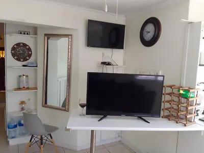 a flat screen tv sitting on top of a white table at Nortey is palace in Cape Town