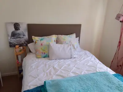 a bed with white sheets and pillows in a bedroom at Nortey is palace in Cape Town