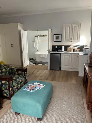 a living room with a blue ottoman in front of a kitchen at On Musson in Hermanus