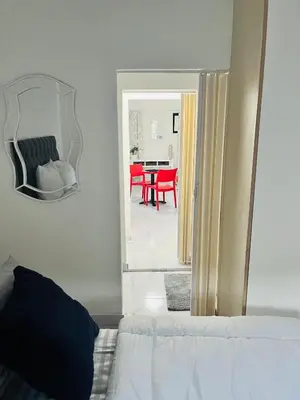 a bedroom with a mirror and a table with red chairs at Self catering one bedroom cottage in Cape Town