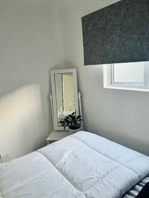 a white bedroom with a bed and a mirror at Self catering one bedroom cottage in Cape Town